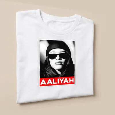 Monochrome portrait of Aaliyah with text in black, white, and red — printed on a unisex t-shirt (angled view)