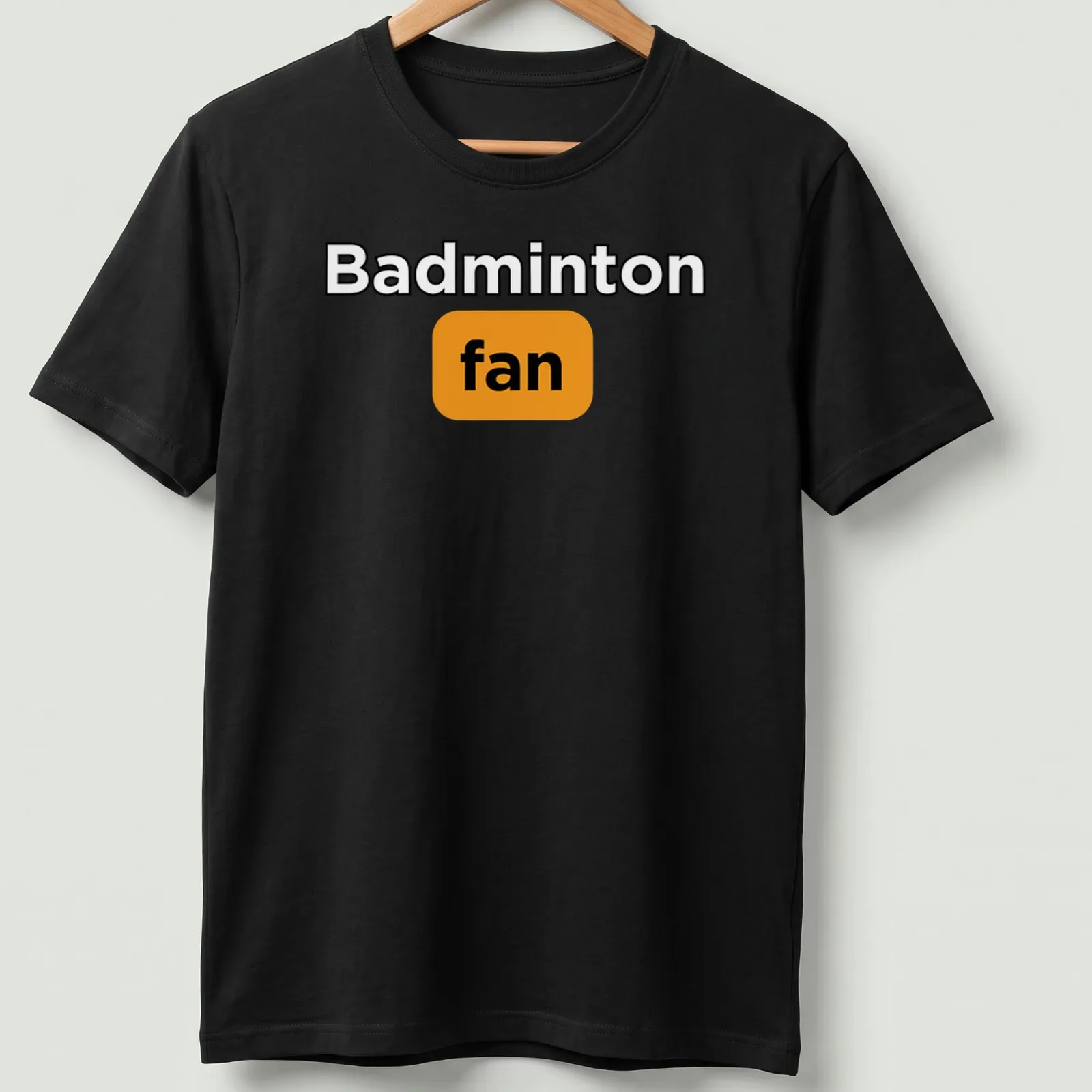 Bold typography Badminton Fan T-shirt in black, orange, and white — printed on a unisex t-shirt