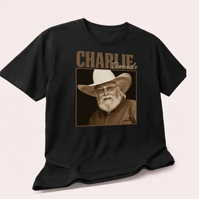 Sepia portrait of Charlie Daniels with text below in classic font — printed on a unisex t-shirt (angled view)