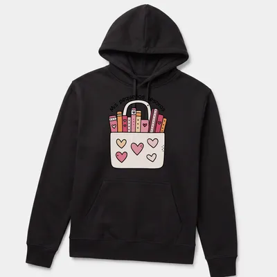 Kawaii illustration of colorful books in a bag with text 'Mis pequeños tesoros' — printed on a unisex hoodie