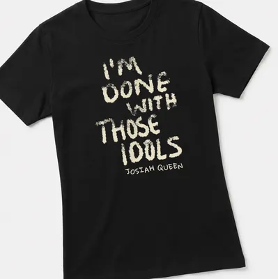 Text-based design featuring dusty bibles with the quote 'I'm Done With Those Idols Josiah Queen' — printed on a women's shirt