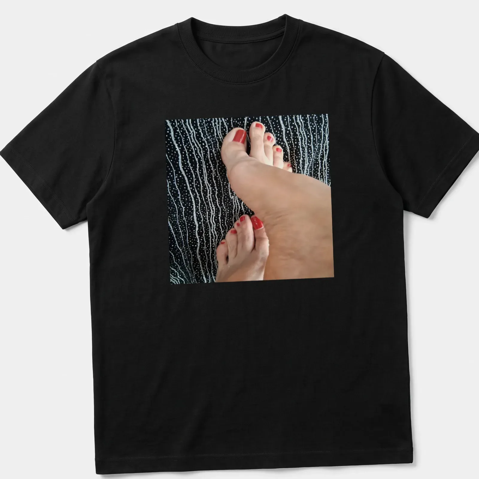 Photographic T-shirt featuring feet with red nail polish on a black background — printed on a unisex t-shirt