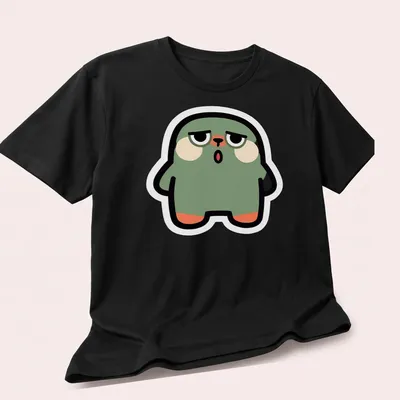Flat design of a cute green blob monster with peach and black accents — printed on a unisex t-shirt (angled view)