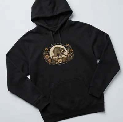 Cottagecore style T-shirt with a whimsical raccoon and the text 'its ok to be weird jimothy from seattle' — printed on a unisex hoodie