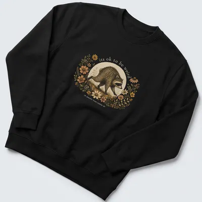 Cottagecore style T-shirt with a whimsical raccoon and the text 'its ok to be weird jimothy from seattle' — printed on a unisex sweatshirt