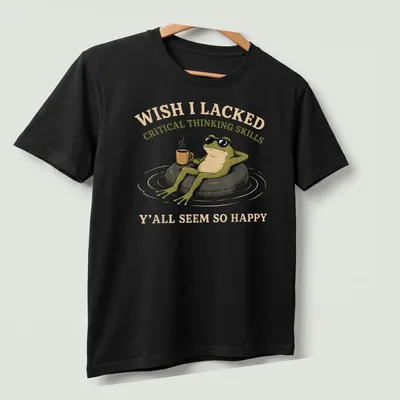Cartoon frog with coffee and humorous text about critical thinking skills — printed on a unisex t-shirt (angled view)