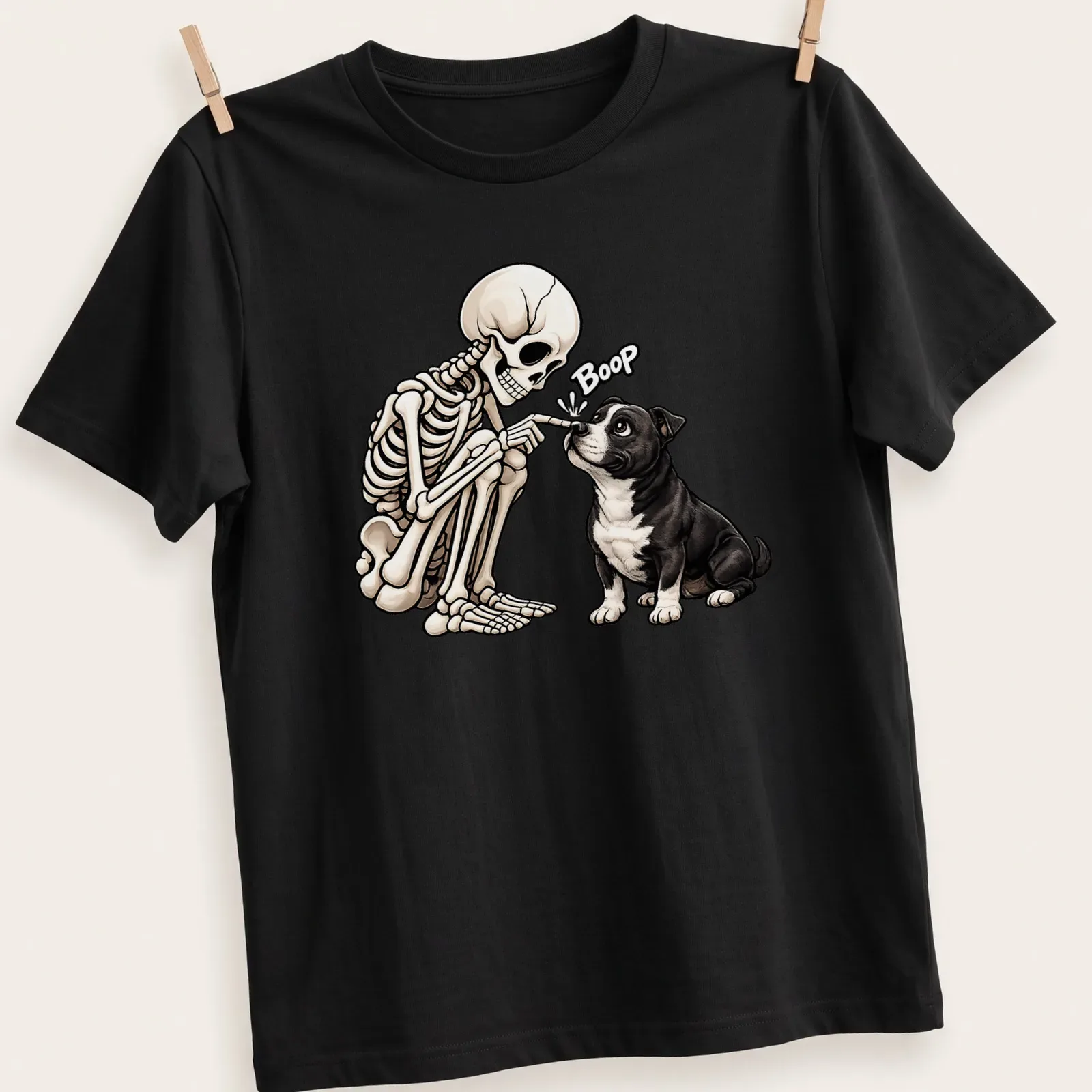 Cartoon Staffordshire Bull Terrier with skeleton, with the word Boop in black and beige — printed on a unisex t-shirt