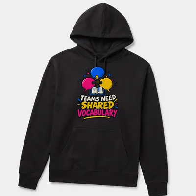 Colorful cartoon graphic with speech bubbles and an open book, stating 'TEAMS NEED SHARED VOCABULARY' — printed on a unisex hoodie