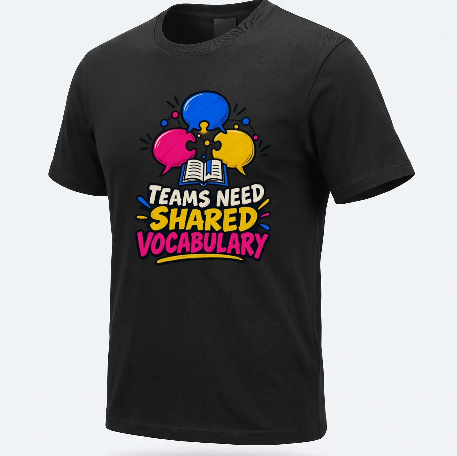 Colorful cartoon graphic with speech bubbles and an open book, stating 'TEAMS NEED SHARED VOCABULARY' — printed on a unisex t-shirt