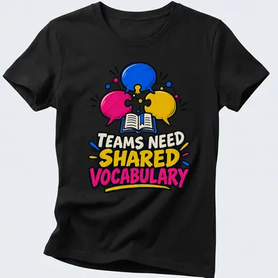 Colorful cartoon graphic with speech bubbles and an open book, stating 'TEAMS NEED SHARED VOCABULARY' — printed on a women's shirt