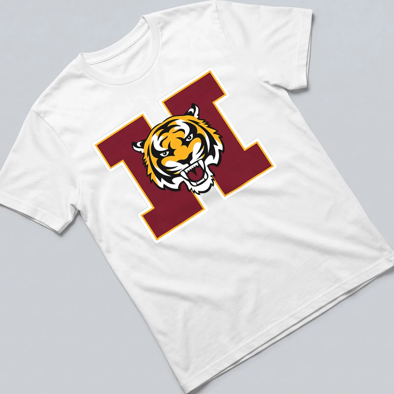 Bold graphic of a tiger mascot in orange, black, and maroon for Harrisburg High School — printed on a unisex t-shirt