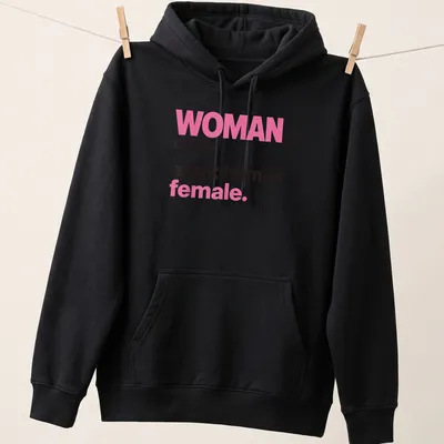 Bold typography t-shirt declaring 'WOMAN noun. adult human female.' in pink and black — printed on a unisex hoodie